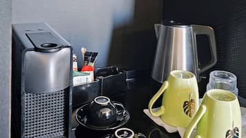 A compact kitchenette with a coffee maker, tea set, and a kettle.