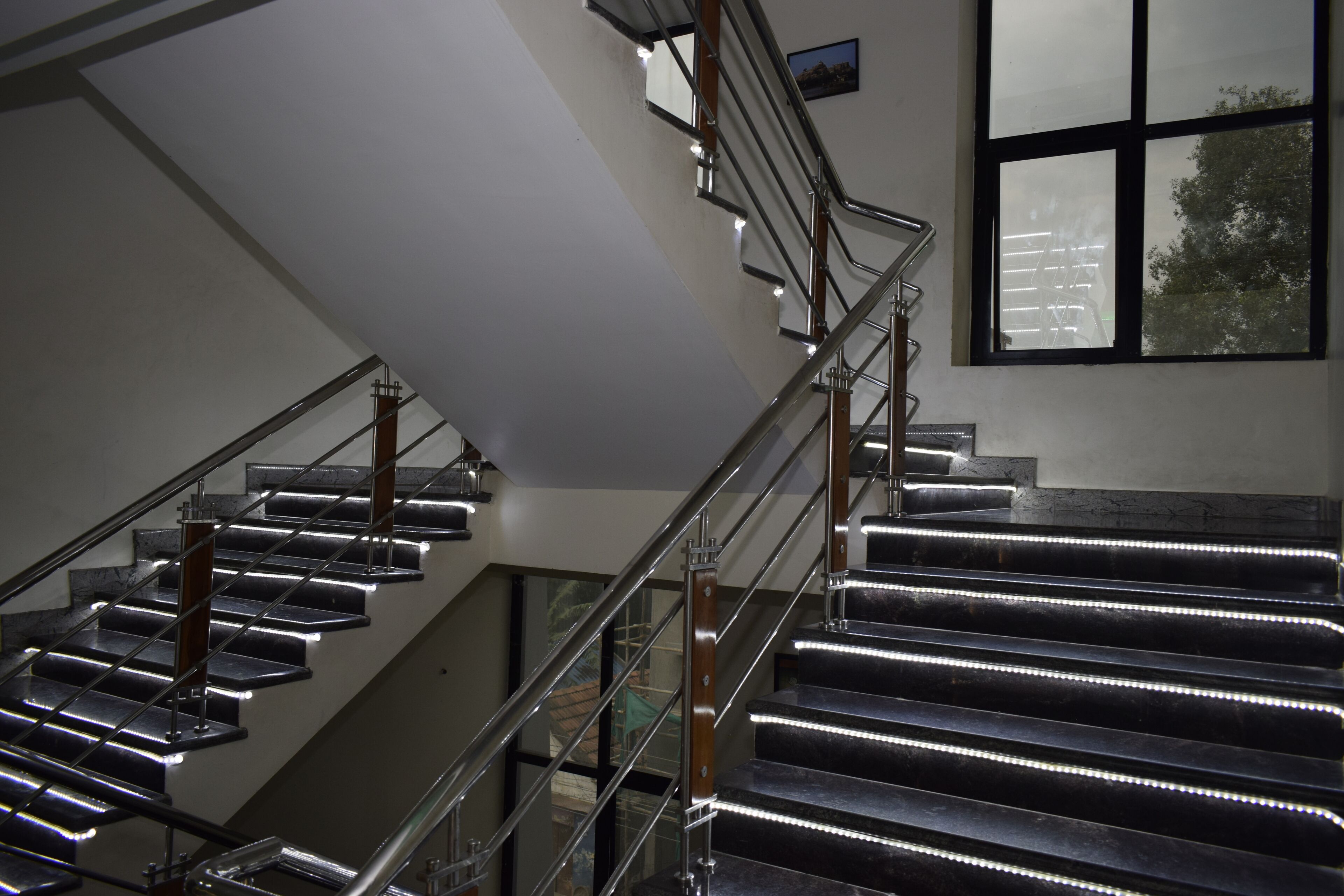 A modern staircase with metal railings and LED lighting.