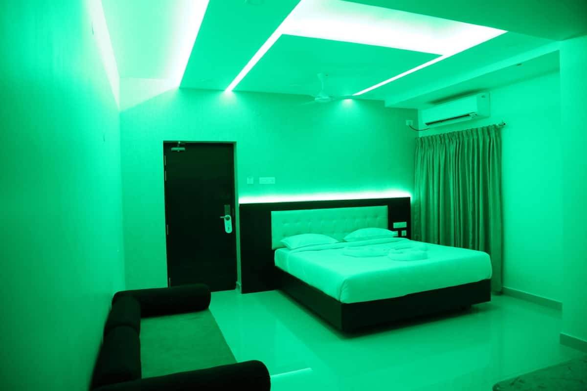 A modern bedroom with a bed, a small seating area, and a ceiling light fixture.