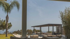 A covered outdoor seating area with a view of the ocean, a pool, and a pergola. - Spacious beach front Vila with 100 sqm infinity pool,  a basket ball court (Rhodes)