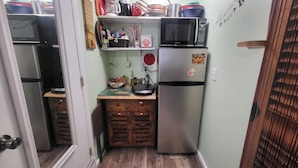 Eine kleine Küche mit Kühlschrank, Mikrowelle und Holzschränken.