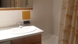A bathroom with a white sink, a mirror, and a shower curtain with a leaf pattern. - Charming 32m² studio, balcony, near slopes, Les Menuires (Les Menuires)