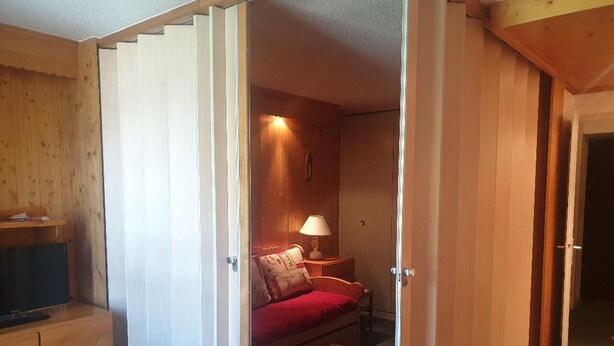 A cozy room with a bed, a nightstand, a lamp, and a small table. - Charming 32m² studio, balcony, near slopes, Les Menuires (Les Menuires)