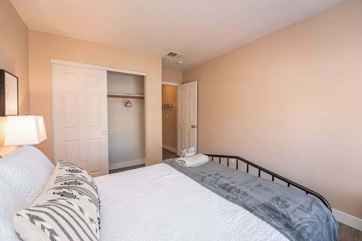 Une chambre à coucher comprenant un lit, une table de chevet, une lampe et une armoire avec une porte.