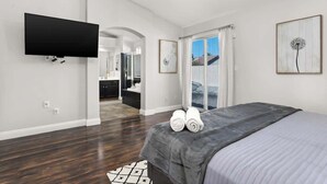 A modern bedroom with a large bed, a flat-screen TV, and artwork on the walls.