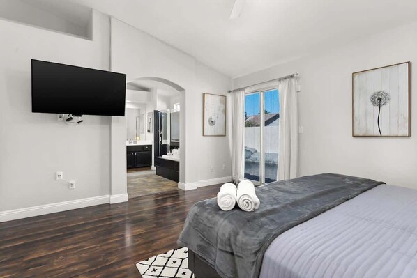 A modern bedroom with a large bed, a flat-screen TV, and artwork on the walls.