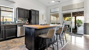 A modern kitchen with dark cabinetry, a wooden island, and bar stools.
