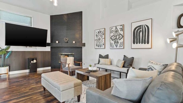 A modern living room with a flat-screen TV, a fireplace, and a sofa set.