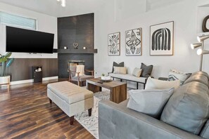 A modern living room with a flat-screen TV, a fireplace, and a sofa set.