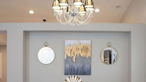 A modern dining area with a wooden table, grey chairs, and a chandelier.