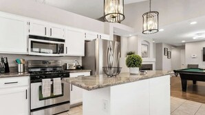A modern kitchen with white cabinetry, stainless steel appliances, and a central island.