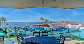 Ein Poolbereich mit Blick auf das Meer, Palmen und einem modernen Pooldesign.