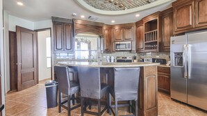 Una cocina con gabinetes de madera oscura, un refrigerador de acero inoxidable y una encimera de granito.