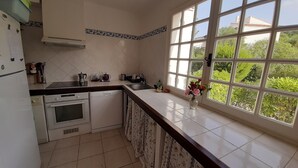 A kitchen with a large window, white cabinets, a stove, and a sink.