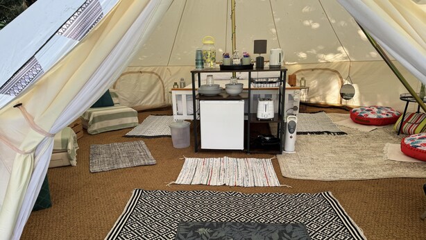 A tent interior with a welcome mat, a small kitchen area, and seating arrangements. - Spacious Bell Tent at Herigerbi Park, Lincolnshire (Grantham)