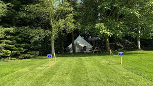 A tented camping area with a grassy field, trees, and two blue signs indicating "Roosbeek Tent" and "Roosbeek Tent." - Spacious Bell Tent at Herigerbi Park, Lincolnshire (Grantham)