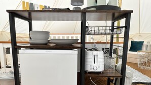 A compact kitchenette with a white mini-fridge, a toaster, and a small table with bowls and a basket. - Spacious Bell Tent at Herigerbi Park, Lincolnshire (Grantham)