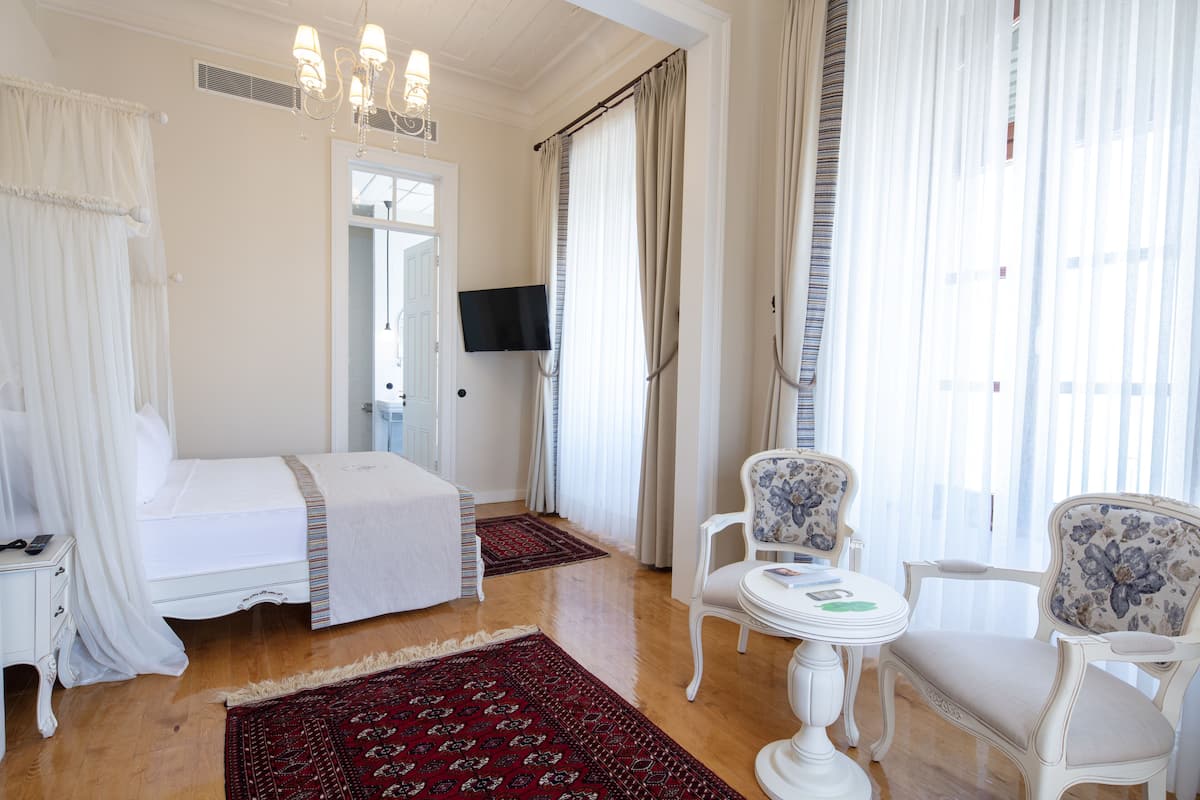 Hotellihuone, jossa on sänky, televisio, tuoli ja pöytä.