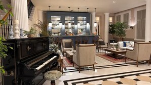 A spacious living room with a grand piano, comfortable seating, a bar area with shelves of bottles, and a staircase leading to an upper level. - Rasim Palas (Adults Only +12) (Cesme)