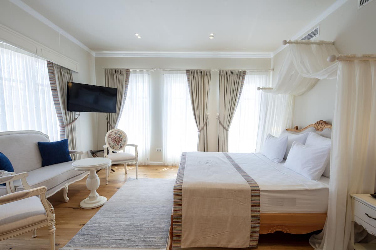 Hotellihuone, jossa on sänky, sohva, televisio ja tuoli.