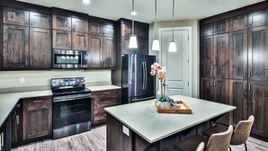 Una cocina moderna con armarios de madera oscura, electrodomésticos de acero inoxidable e iluminación colgante.