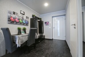 A modern room with a dining table, chairs, a mirror, and a door.