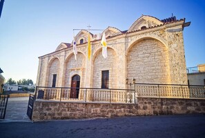 Ein Steinhaus mit drei Rundbogenfenstern und einer mittleren Tür, vermutlich ein historisches oder religiöses Gebäude.