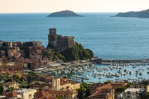 A coastal town with a historic castle on a hill, a marina with numerous boats, and a densely built urban area with traditional architecture. - Beach House, 300 m dal mare, Marina di Massa, free bike, wifi, air conditioning (Marina di Massa)