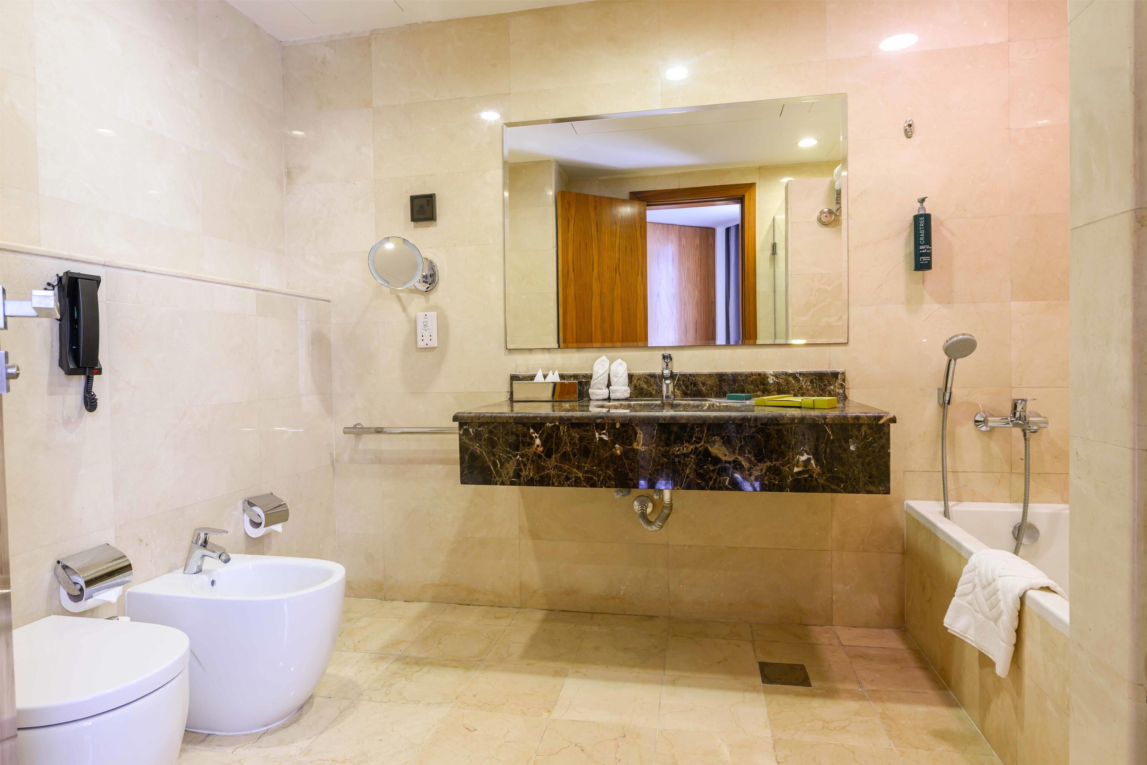 Une salle de bain moderne avec un meuble-lavabo en marbre, une baignoire sur pieds et un lavabo séparé.