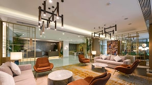 Een moderne hotel lobby met een receptiebalie, zithoek en decoratieve verlichting.