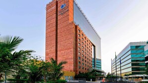 Een hoog, modern hotel met een opvallende rode gevel en een groot glazen gedeelte.