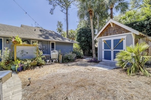 A house with a covered patio, a small shed, and a garden with various plants.