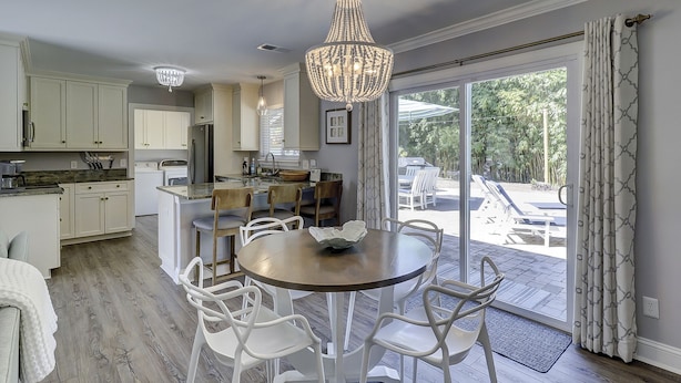 A modern kitchen with white cabinets, a central island, and a chandelier.