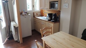 Ett kompakt kök med träskåp, ett vitt kylskåp, en mikrovågsugn och en diskho.
