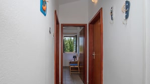 Un couloir étroit, avec des portes en bois et une fenêtre au fond.