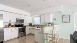 A modern kitchen with white cabinets, stainless steel appliances, and a wooden floor.