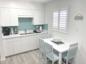 Enjoy cooking in this well-equipped kitchen with a double sink, coffee maker, and dish rack, adjacent to a dining area with a table and chairs.