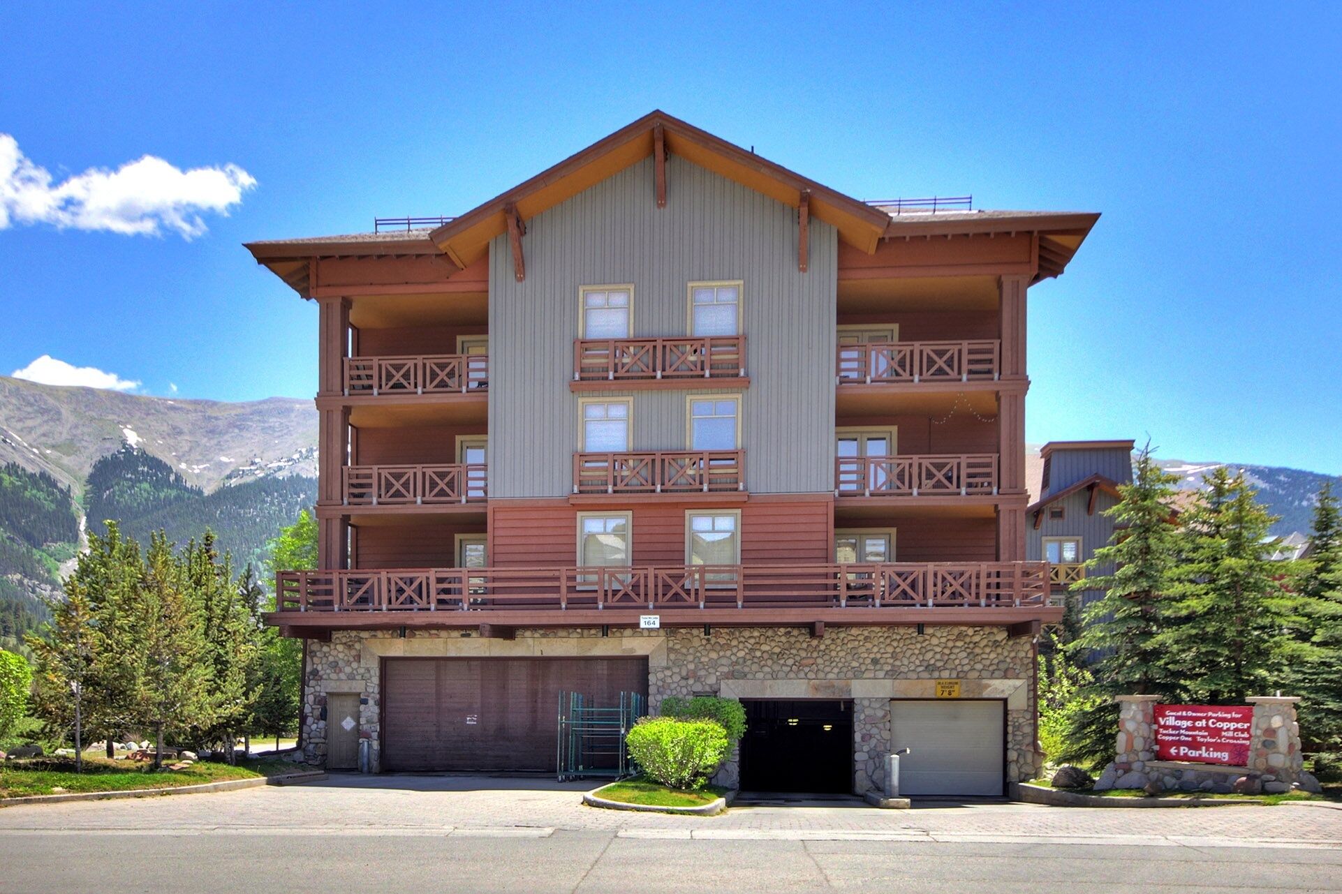 A multi-story hotel with balconies, a stone facade, and a parking area.