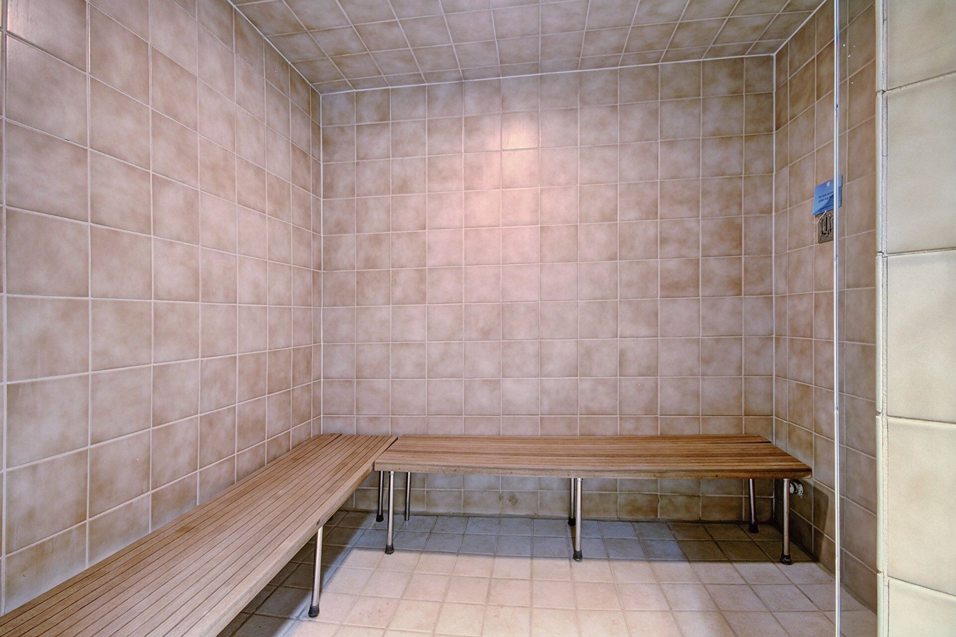 A sauna with two wooden benches and tiled walls.