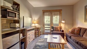 A compact living space with a kitchenette, a sofa, a coffee table, and a TV. - Modern Hotel Room in Center Village - TM225A by Redawning (Copper Mountain)