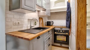 A compact kitchen with white cabinets, a wooden countertop, a sink, a coffee maker, and a stove. - Villa Bougainvillier - quays of Trouville-sur-Mer (Trouville-sur-Mer)