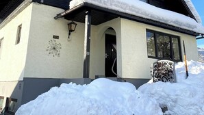 Un bâtiment à deux étages, avec un toit recouvert de neige et un petit porche.