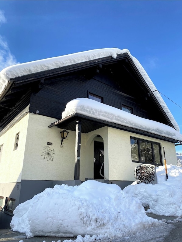 Un bâtiment à deux étages, avec un toit recouvert de neige et un petit porche.