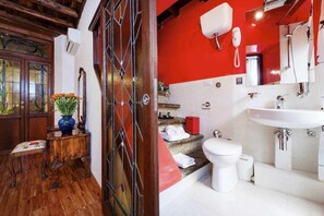 A bathroom with a red wall, white sink, and a mirror. - Apartment (Roma)