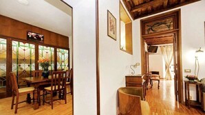 A dining area with wooden furniture and a large window with stained glass. - Apartment (Roma)