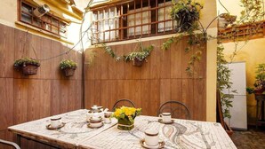 A dining table set with tea cups and saucers, surrounded by chairs, in a room with wooden walls and hanging plants. - Apartment (Roma)