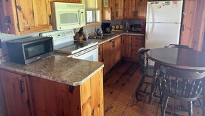 Une cuisine équipée de meubles en bois, d’un four à micro-ondes, d’une cuisinière, d’un évier et d’un réfrigérateur.