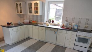 Cozinha com armários brancos, bancada preta e piso de azulejos.