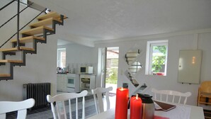 Uma cozinha moderna com armários brancos, forno embutido e um espaço de jantar com uma mesa branca posta para dois.