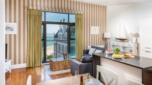 A modern living room with a glass door leading to a balcony overlooking a beach.